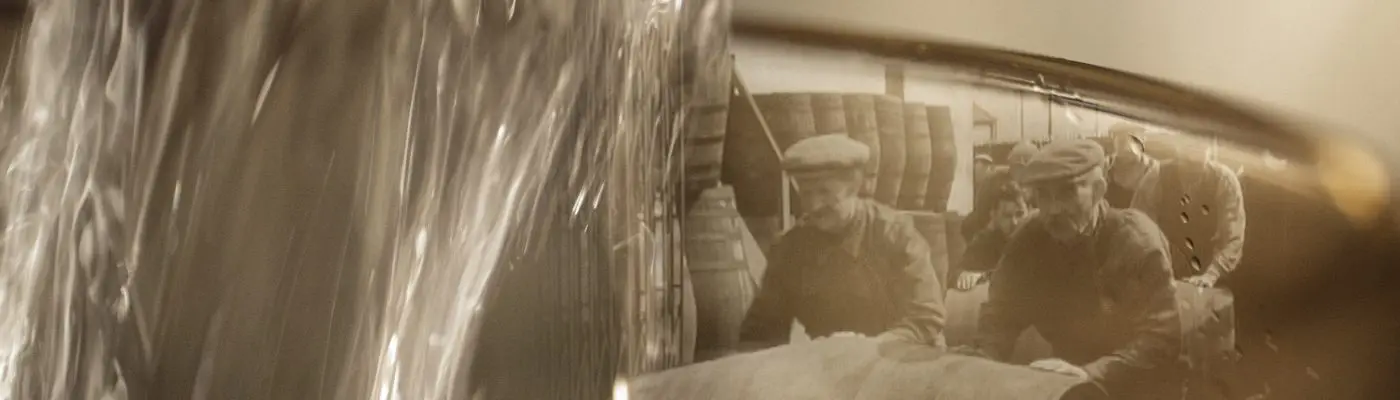 Old image of whisky workers at The Dalmore distillery rolling barrels